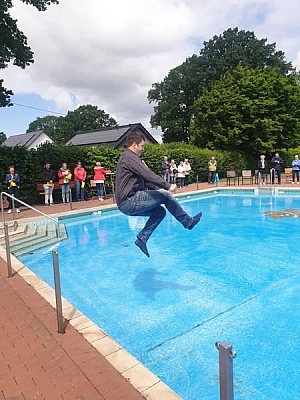 Mann springt mit Kleidung in Schwimmbecken