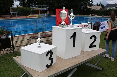 Pokale und Siegertreppchen vor Schwimmbecken