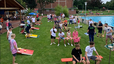 Cornhole-Turnier auf Wiese neben Schwimmbecken
